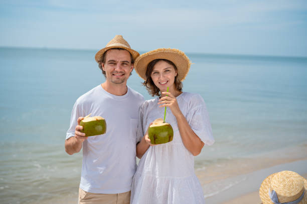 istock Couple enjoys refreshing coconuts on the beach during a sunny day by the water 2201406363