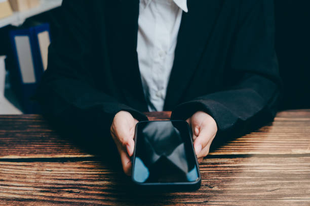 istock Business Professional Presenting Smartphone on Wooden Table Surface, business concept 2201409070