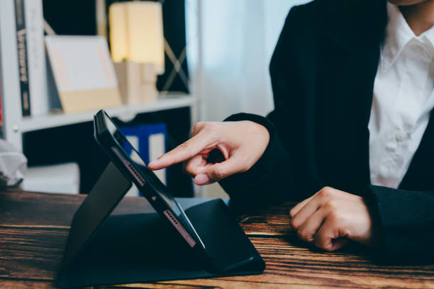 istock Person Using Tablet Device While Sitting at Wooden Desk with Focus, business concept 2201409238