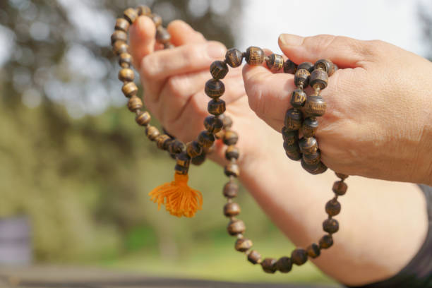 istock woman praying with a wooden mala beads in her hands 2201410324