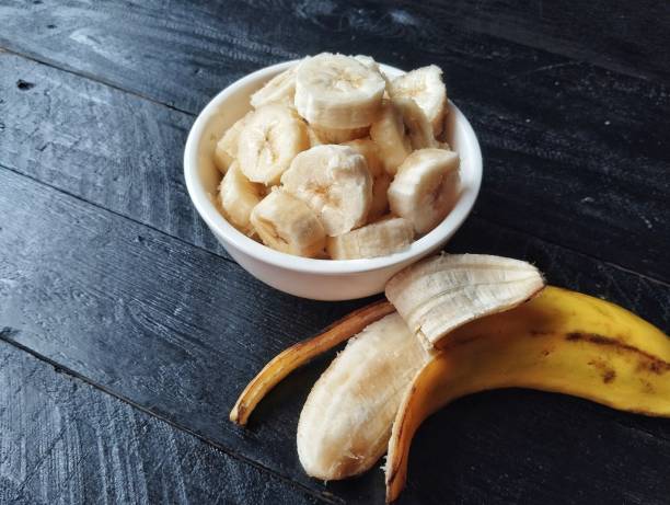 istock Fresh slice bananas in bowl on black wooden table background 2201410770