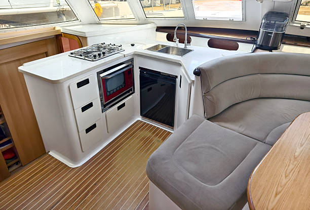 A cozy living room and kitchen featuring a stylish curved couch and a table located on sailing boat