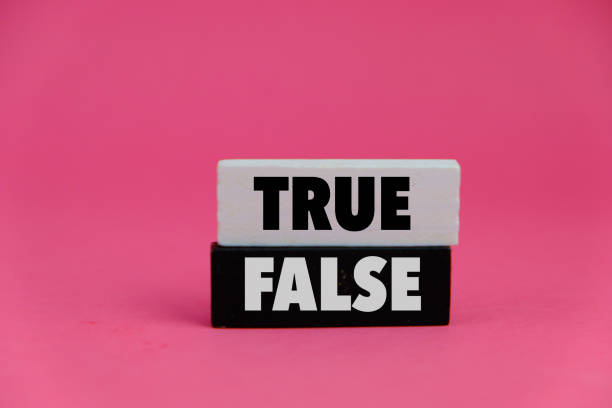 istock A black and white wooden block on pink background and word TRUE, FALSE 2201421117