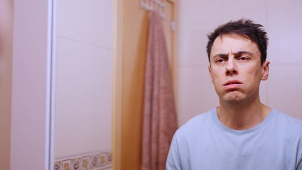 istock Sleepy man feeling exhausted and frustrated in bathroom mirror 2201421198