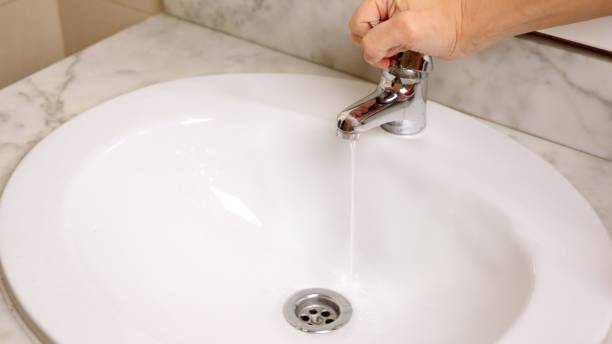 istock Hand opening water tap in sink, showing water shortage concept 2201422361