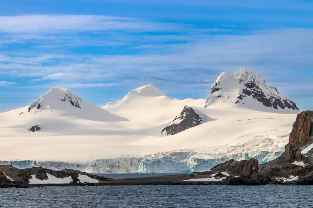 istock Snow covered mountain, Antarctica. Rocks, blue ice. Blue sky, lcouds. 2201426499