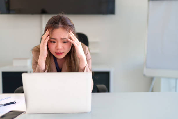 istock Young Asian businesswoman feeling stressed while looking at her laptop and analyzing problems at work 2201430003