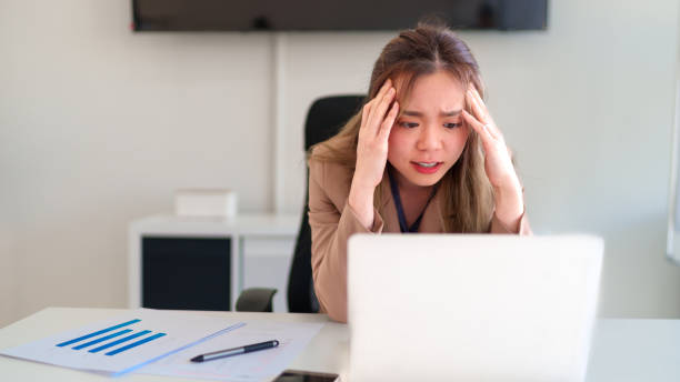 istock Young Asian businesswoman feeling stressed while looking at her laptop and analyzing problems at work 2201430008