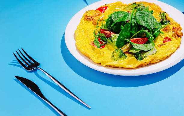 istock Delicious vegetable omelette garnished with fresh spinach on a bright blue background 2201434264