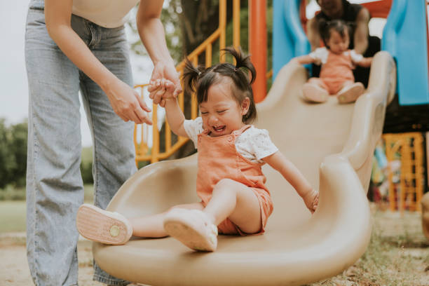 istock Smiles and Support: Parents Assist Twins on a Slide 2201434401