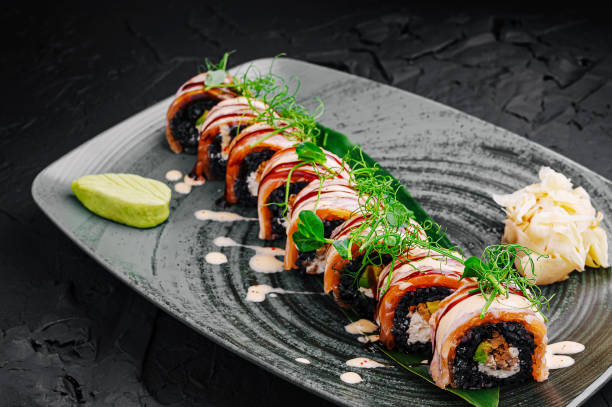 istock Exquisite sushi rolls beautifully arranged on a modern black plate with garnishes 2201437536