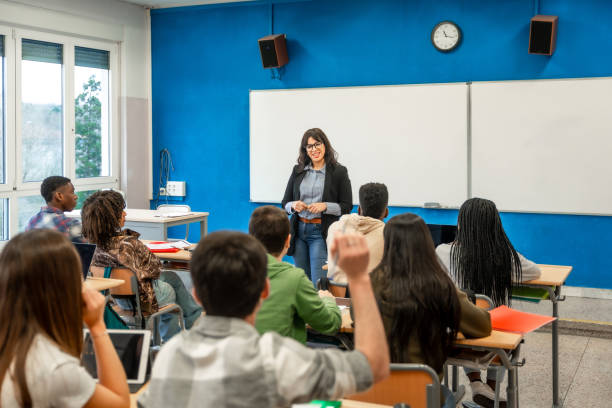 istock High school teacher giving lesson to students raising hands 2201440817