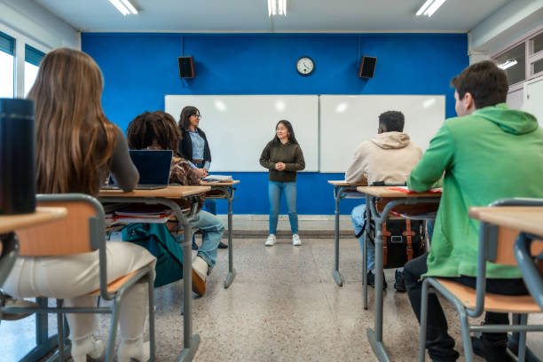 Teen student giving presentation to classmates in high school