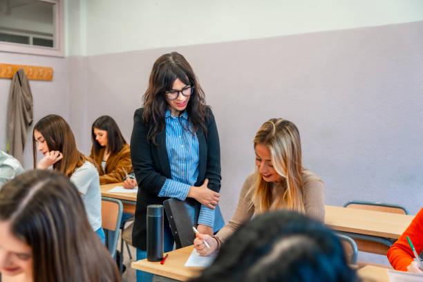 istock Teacher helping young adult student during exam at university 2201440893