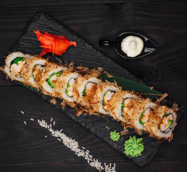 istock Tempura sushi roll being served on black slate platter 2201442514