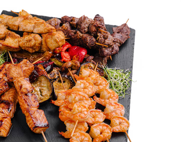 istock Grilled skewers featuring shrimp, beef, and chicken served on a slate platter with vegetables 2201442639