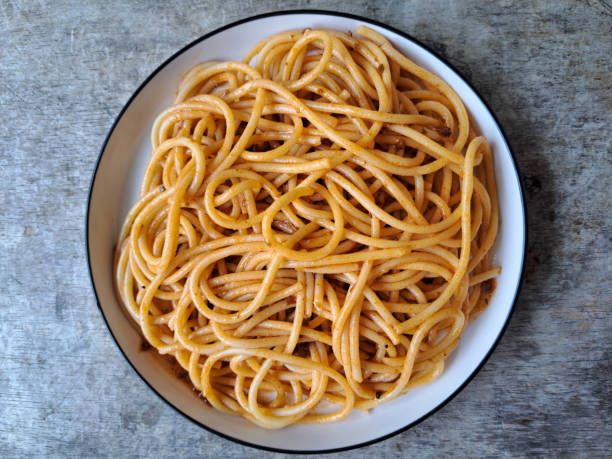 A portion of cooked spaghetti with red tomato sauce isolated on a white background