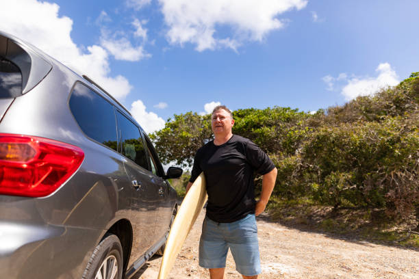 istock Middle Aged Man Unloading a Surfboard from a 4WD Car at the Beach 2201446645