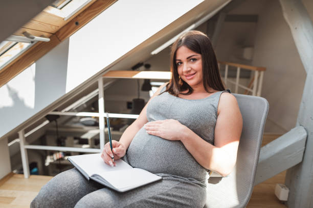 istock pregnant woman writing on the diary at home 2201448821