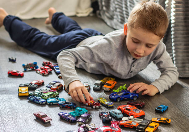 Bangkok, Thailand - November 18, 2014: A little thai boy is playing with toy cars on table on sidewalk in Bangkok.