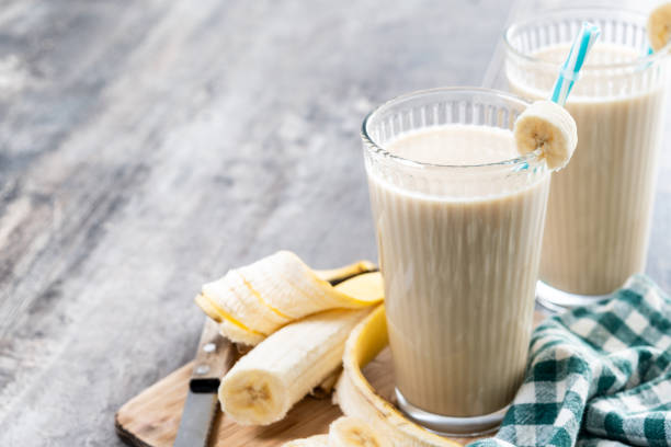 istock Fresh banana smoothie on white wooden table. 2201451258