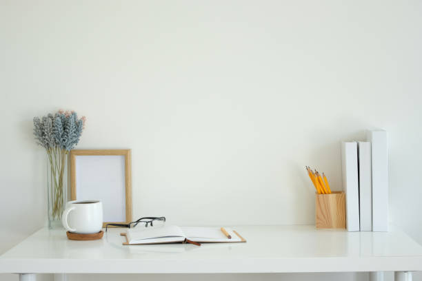 istock White desk featuring an open notebook, a white coffee mug, glasses, and a pencil. 2201451302