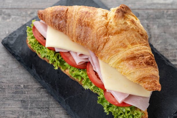 istock Croissant with ham, cheese and vegetables on wooden table 2201451363