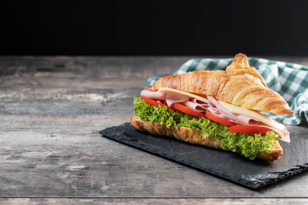 istock Croissant with ham, cheese and vegetables on wooden table 2201451387