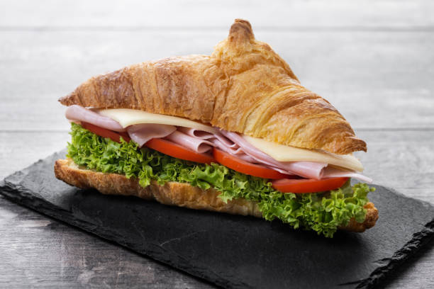 istock Croissant with ham, cheese and vegetables on wooden table 2201451456