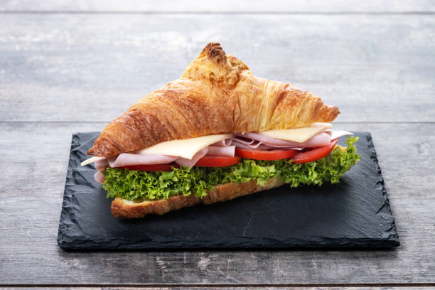 istock Croissant with ham, cheese and vegetables on wooden table 2201451477