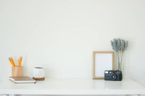 istock Empty wooden photo frame, coffee mug, and camera on white working desk. 2201451486