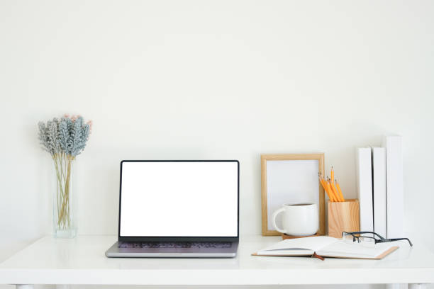istock Office desk with a laptop, open notebook, and coffee mug, complemented by decorative items such as a wooden photo frame, lavender in a glass vase, and a pencil holder with vibrant pencils. 2201451497