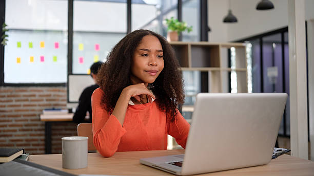 istock Creative workspace featuring a confident woman engaged in her work on a laptop, perfect for themes of remote work or modern offices. 2201452329
