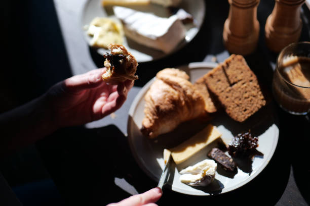 istock Sunny breakfast with dark rye bread, croissant, coffee and cheese on wooden table 2201460120