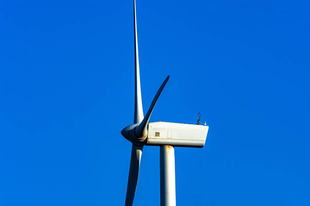 Large wind turbine with rotating blades against a clear blue sky. renewable energy infrastructure. Side view.