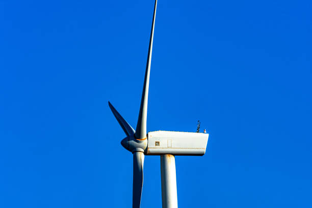 Large wind turbine with rotating blades against a clear blue sky. renewable energy infrastructure. Side view.