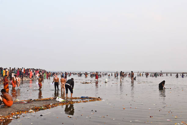 Pilgrims line the riverbank, engaging in prayers and spiritual cleansing rituals.