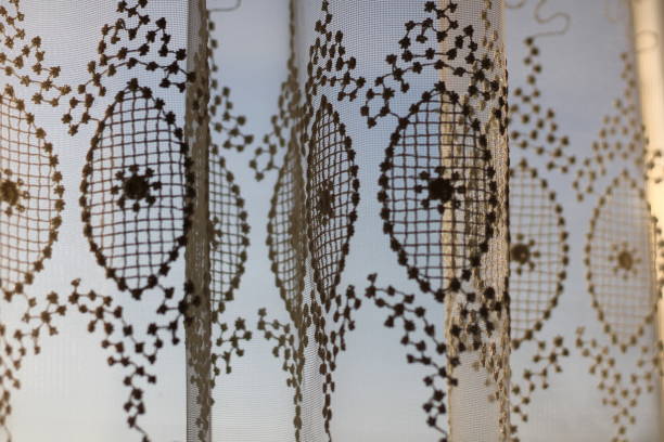 An old yellow clear curtain with abstract and floral design decorations hanging on the ceiling, wallpaper background