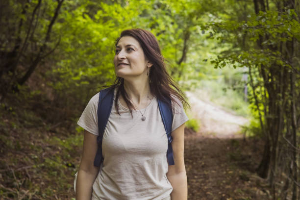 Connecting with nature. Woman backpacker exploring forest.  Precious moments while enjoying her adventure in parkland.