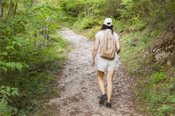 Connecting with nature. Woman backpacker exploring forest.  Precious moments while enjoying her adventure in parkland. Woman has diabetes and she is wearing small sensor on the back of upper arm for controlling blood sugar. Travel with chronic illness.