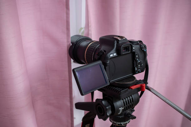 istock Digital video camera hidden behind pink curtains, spying neighbors Peeping. Spying. Surveillance.   Hidden Camera.   Paparazzi.  Private Detective. Stalker concept 2201473151