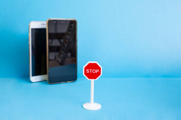 istock Two defocused smartphones and a stop road sign on blue blurred background 2201473195