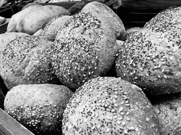 Close-up of a freshly baked bread loaf topped with sesame seeds, emphasized by the bright surface. The bread, made in a Mallorca bakery, Spain, evokes tradition, natural ingredients, and craftsmanship.