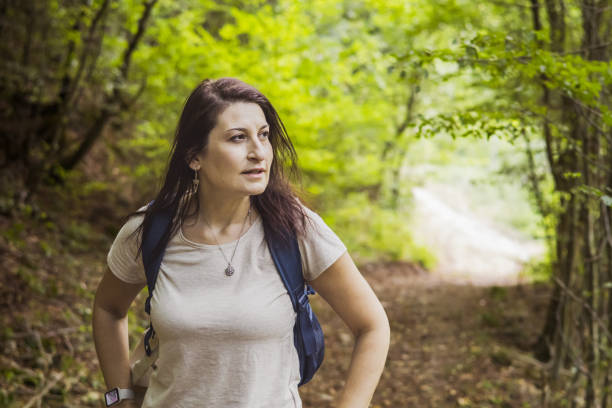 Connecting with nature. Woman backpacker exploring forest.  Precious moments while enjoying her adventure in parkland.
