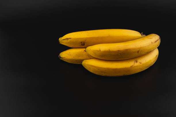 istock Fresh bananas stacked on a dark background in a simple arrangement 2201475236