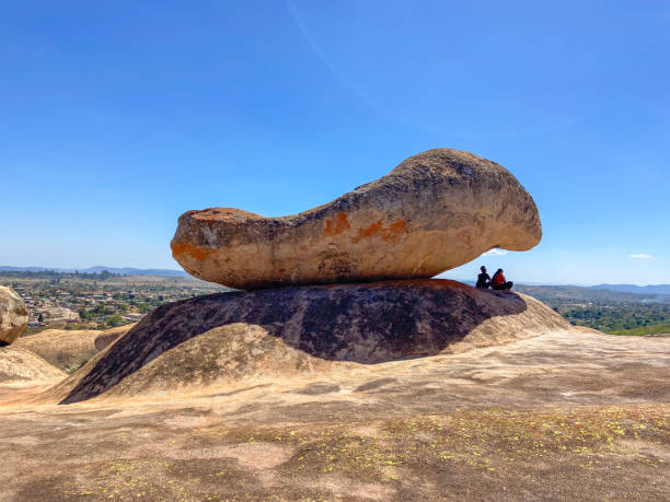 Domboshawa, Zimbabwe - May 1 2024: people sit under the naturally occurring balancing rocks on top of Domboshawa (also known as Domboshava).