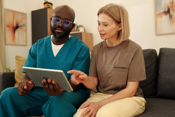 istock Educating Senior Woman with Tablet Device in Living Room 2201479812