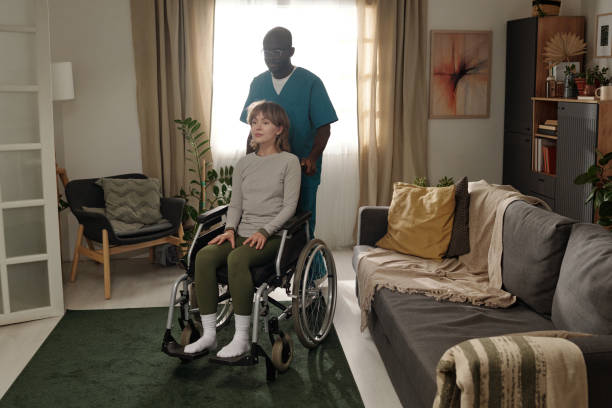 istock Assisting Woman in Wheelchair in Comfortable Home Setting 2201479840