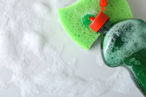 istock Open detergent bottle spilling detergent onto a green scouring pad 2201480371