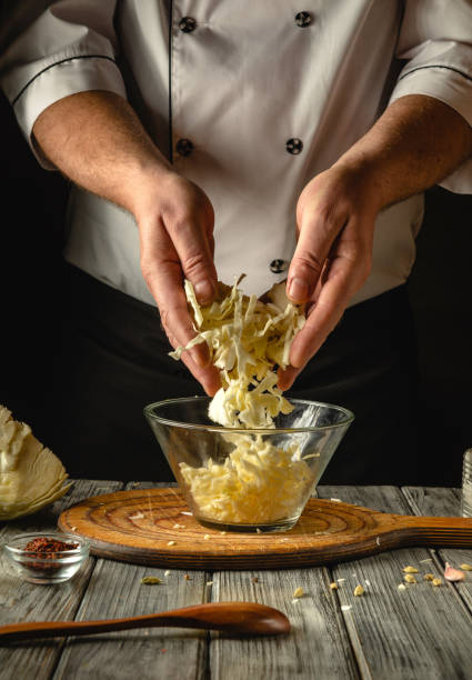 istock Skilled hands shred crisp cabbage while preparing a traditional coleslaw in a warm, inviting kitchen. The wooden table holds various ingredients, enhancing the culinary atmosphere 2201482859